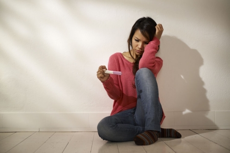 24717006_m-Women and health, anxious Asian girl looking at pregnancy test kit 24717006 - women and health, anxious asian girl looking at pregnancy test kit, sitting on ground at home