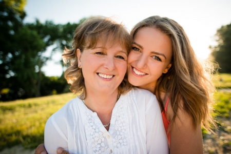 44585406 - portrait of mother and her teenage daughter outdoor in nature with setting sun in background